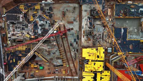 A-busy-construction-site-with-cranes,-machinery,-and-building-materials,-aerial-view