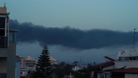 Time-lapse-of-a-thick-black-smoke,-after-a-missile-attack-in-Israel,-wildfire-burn,-buildings-and-trees-in-the-background,-4k-video