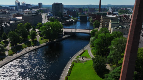 Drone-tilting-over-the-Tammerkoski-river,-toward-downtown-Tampere,-summer-in-Finland