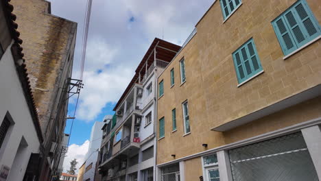 A-street-view-in-Nicosia,-Cyprus,-showcasing-a-mix-of-old-and-new-buildings-with-balconies-and-colorful-shutters