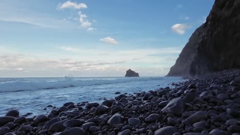 Kiesstrand-Mit-Wellen,-Die-An-Den-Strand-Krachen,-Und-Den-Klippen-Dahinter-Mit-Blick-Auf-Das-Meer-Und-Den-Ozean-Auf-Einer-Insel