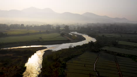 Picturesque-aerial-view-flying-over-mist-covered-farm-fields-in-rural-Thailand