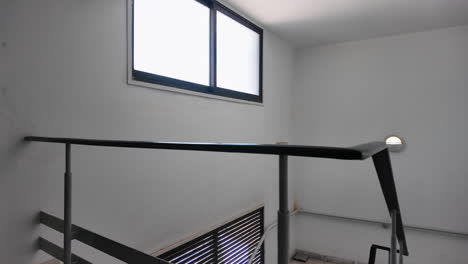 An-interior-view-of-a-modern-staircase-in-Nicosia,-Cyprus,-with-sleek-metal-railings-and-large-windows-allowing-natural-light-to-flood-in