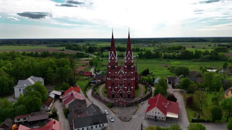 Sveksna-church-in-lithuania-surrounded-by-lush-greenery-and-quaint-buildings,-aerial-view