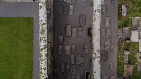 Claregalway-Friary-cemetery-tombstones-fallen-over-lying-on-back,-aerial-top-down-bird's-eye-view-of-tower