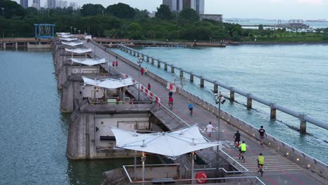 A-healthy-lifestyle,-people-riding-bike,-jogging,-strolling-across-the-reservoir-at-Marina-Barrage,-serves-as-a-water-management-facility-for-irrigation,-flood-control,-and-water-supply-in-Singapore