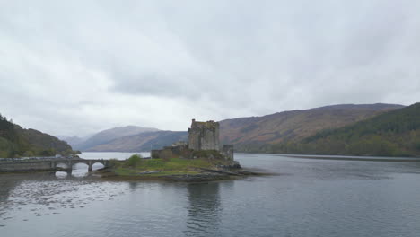 Aerial-circling-Eilean-Donan-Castle-on-cloudy-day,-Scotland