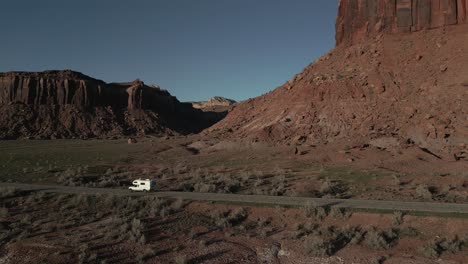 White-campervan-driving-on-UT-211-road-in-indian-creek-climbing-area,-Utah,-USA