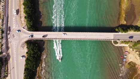 Autos-Fahren-über-Stille-Bay-Bridge,-Motorboot-Fährt-Darunter-Durch,-Luftaufnahme-Von-Oben-Nach-Unten