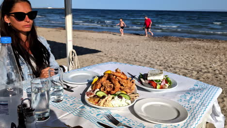 A-young-woman-having-a-seafood-diner-at-a-beach-restaurant-in-Greece