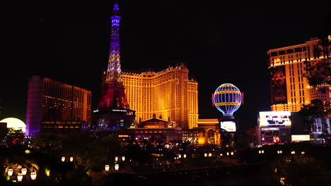 Shiny-Las-Vegas-Strip-at-NIght,-Lights,-Eiffel-Tower-and-Paris-Balloon-Replica,-Casino-and-Hotels