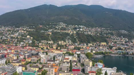 Drone-Aerial-over-Locarno-in-Switzerland-showcases-a-vibrant-town,-lake,-and-stunning-mountain-views