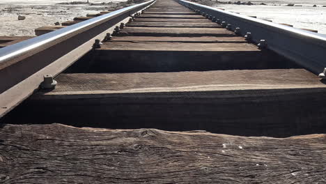 Low-dolly-along-metal-tracks-with-wooden-support-beams-in-desert-of-Bolivia