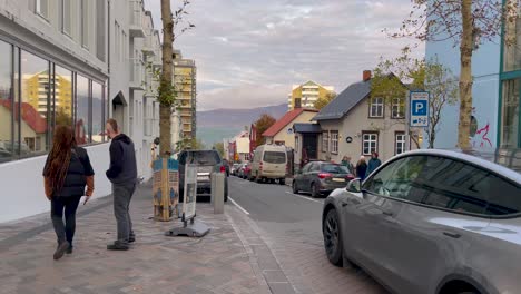 People-walk-in-streets-of-Reykjavik-in-cozy-evening-light,-static-view