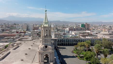 Sea-Testigo-De-Una-Magnífica-Vista-Panorámica-De-Las-Torres-De-La-Catedral-De-Arequipa-En-Una-Emocionante-Panorámica-De-Izquierda-A-Derecha,-Con-El-Imponente-Volcán-Brumoso-Al-Fondo.