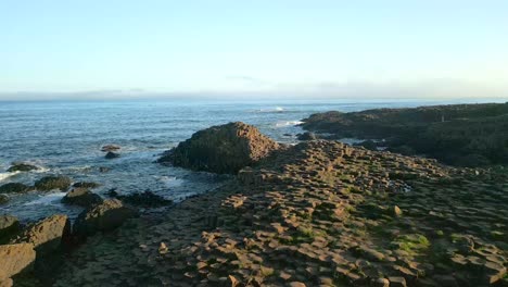 Toma-Aérea-De-Las-Piedras-De-Basalto-En-La-Calzada-Del-Gigante-En-El-Condado-De-Antrim,-Irlanda-Del-Norte-Al-Amanecer.