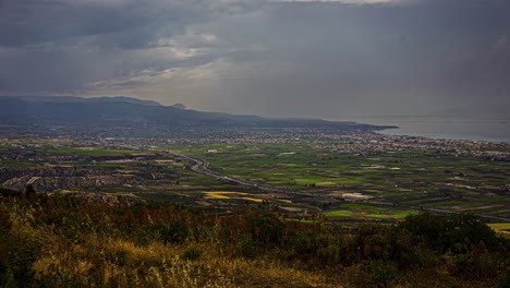 Lapso-De-Tiempo-Que-Establece-El-Paisaje-Rural-Del-Pueblo,-Fondo-Montañoso,-Nubes-En-Movimiento,-Autos-Conduciendo