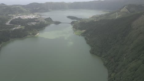 Sete-cidades-lakes-in-portugal,-surrounded-by-lush-green-hills-and-a-distant-village,-aerial-view