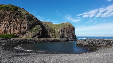 Round-pool-next-to-the-sea-and-ocean,-very-calming-and-cliffs-in-the-background