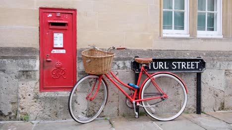 Traditioneller-Roter-Briefkasten-Und-Rotes-Vintage-Fahrrad-Mit-Weidenkorb-In-Der-Historischen-Turl-Street-In-Oxford,-England,-Großbritannien