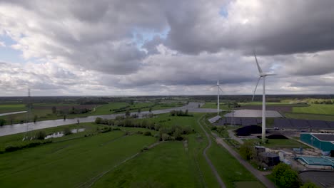 Pan-reveal-aerial-of-clean-energy-wind-turbines-solar-panels-and-water-purifying-facility-hub-in-agrarian-Dutch-landscape-seen-from-above