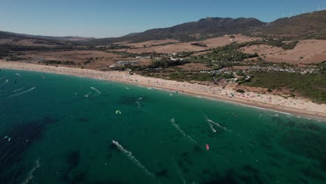 Dolly-Links:-Luftbildvideo-Von-Kitesurfern,-Die-An-Einem-Sonnigen-Tag-Am-Strand-Von-Tarifa,-Cadiz,-Spanien,-üben-Und-Spaß-Haben