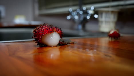 Curious-lizard-walks-around-licking-rambutan-fruit-left-on-countertop