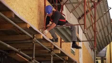 Construction-worker-hanging-on-statement-working-on-exterior-of-a-residential-building-in-Venice