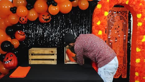 Latino-man-putting-marigold-flowers-in-wooden-box-on-Halloween-altar