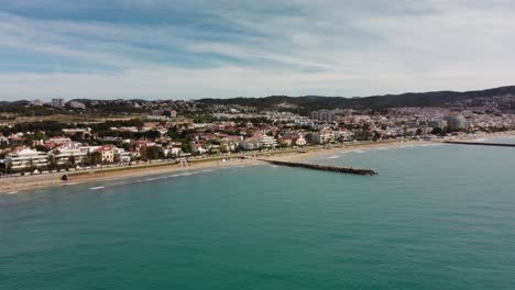 Scenic-aerial-view-of-Sitges,-Spain's-coastline-and-cityscape-on-a-clear-day