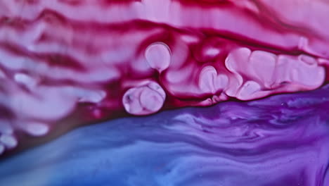 Vibrant-red-and-purple-ink-swirling-and-merging-underwater,-creating-fluid-abstract-patterns
