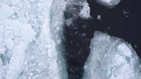 Vista-De-Arriba-Hacia-Abajo,-Navegando-En-Agua-De-Mar-ártico-Cubierta-De-Trozos-De-Hielo-Rotos,-De-Cerca