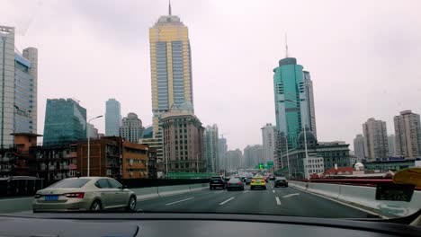 China,-Shanghai:-The-video-captures-an-urban-view-from-inside-a-taxi,-showcasing-the-bustling-streets-of-Shanghai-and-the-surrounding-skyscrapers