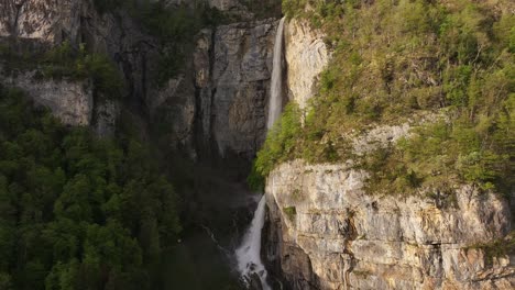 Vista-Aérea-De-Las-Cataratas-Seerenbach,-Que-Caen-En-Cascada-Por-Un-Acantilado-Escarpado-Rodeado-De-Exuberante-Vegetación,-Ubicado-Cerca-De-Betlis-En-El-Municipio-De-Amden,-Suiza