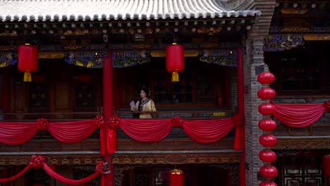 Qing-girl-looking-from-balcony-with-typical-Chinese-red-lanterns-in-Pingyao