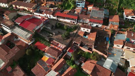 Enjoy-a-stunning-descending-aerial-shot-towards-San-Blas-Lookout,-showcasing-the-Tejas-roofs-and-green-courtyards-in-Cusco