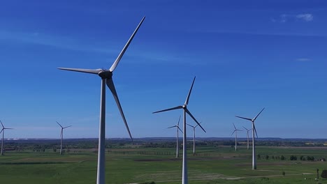 Wind-turbines-rotating-on-a-vast-green-field-under-a-clear-blue-sky