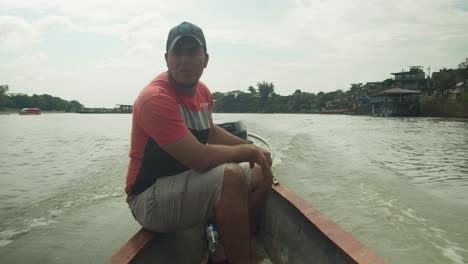 Man-steering-a-motorboat-on-a-river-in-Florencia,-Colombia-on-a-cloudy-day