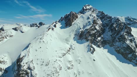 Beautiful-blue-sky,-rock-erosion,-mountain-summit,-drifting-snow,-aerial