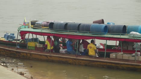 People-loading-cargo-onto-a-boat-in-Florencia,-Colombia,-by-the-riverbank