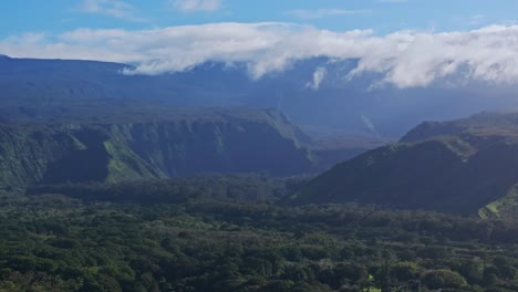 Wide-aerial-pan-of-green-hilly-landscape-and-clouds-on-sunny-Maui,-Hawaii