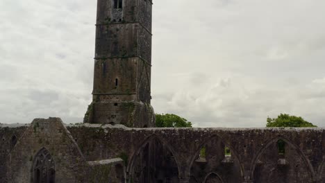 Claregalway-Kloster-In-Der-Mitte-Mit-Dunklen,-Stimmungsvollen-Farben,-Während-Sich-Die-Drohne-Zu-Verwitterten-Steinmauern-Bewegt