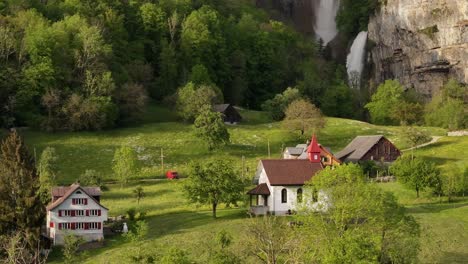 A-picturesque-Swiss-village-with-traditional-houses-and-a-charming-church-sits-at-the-foot-of-Seerenbach-Falls