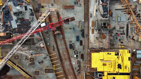 A-busy-construction-site-with-cranes-and-building-materials-during-the-day,-aerial-view