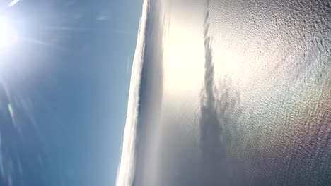 Vertikale-Luftaufnahme-Des-Blauen-Himmels-Und-Des-Meeres-An-Einem-Klaren-Tag-Mit-Strahlendem-Sonnenschein-Und-Sanften-Wasserwellen