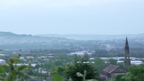 Landscape-View-Over-Welsh-Town-with-Church-Spire-and-Foggy-Hills-Background