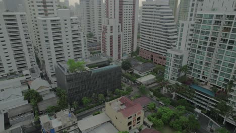 Aerial-fly-in-shot-of-modern-hotel-building-with-rooftop-pool,-Bangkok