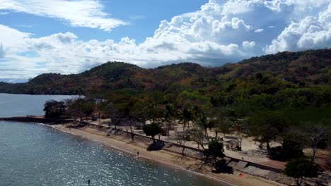 Philippines,-Coron:-The-video-captures-an-aerial-view-of-a-beach-in-Coron,-showcasing-its-white-sand,-crystal-blue-water,-and-a-stunning-sky-with-fluffy-clouds