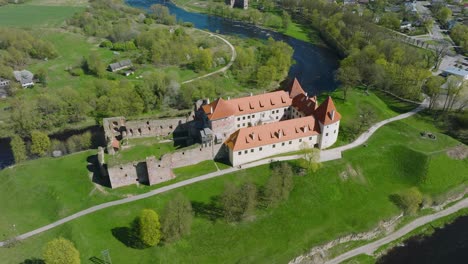 Vista-Aérea-Del-Castillo-Medieval-Y-Las-Ruinas-De-Bauska,-Los-Ríos-Musa-Y-Memele-Junto-Al-Castillo,-Día-Soleado-De-Primavera,-Disparo-De-Drone-En-órbita