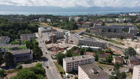 Drone-slowly-flies-towards-a-construction-site-with-newly-built-buildings-with-photovoltaic-solar-panels-on-rooftop